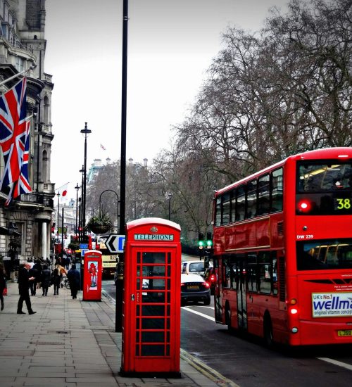 Classic London scene featuring a red double-decker bus and iconic phone booth on a busy city street.