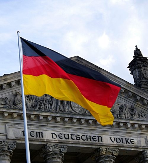 German national flag waving in front of the Reichstag building in Berlin, a symbol of democracy.