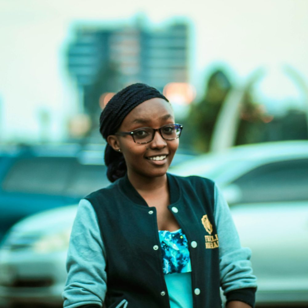 Smiling woman wearing glasses and a jacket outdoors in Nairobi, Kenya. Urban background.