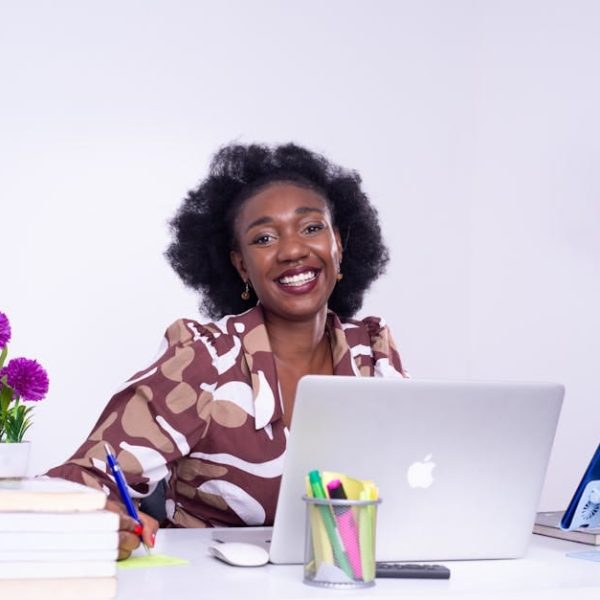 A cheerful African businesswoman working at her desk in Kinshasa, showcasing a lively professional workspace.