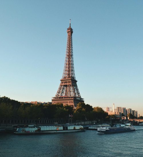 Scenic view of the Eiffel Tower and Seine River at sunset, showcasing iconic Parisian architecture.
