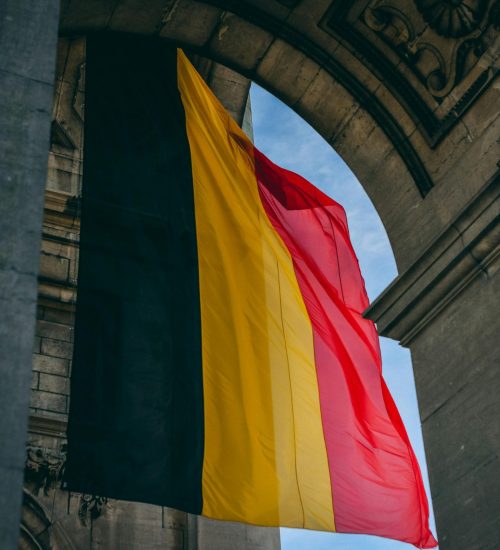 Vibrant Belgian flag under iconic archway in Brussels, symbolizing national pride.