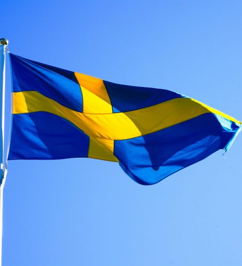 Bright Swedish flag waving on a clear day with blue sky.