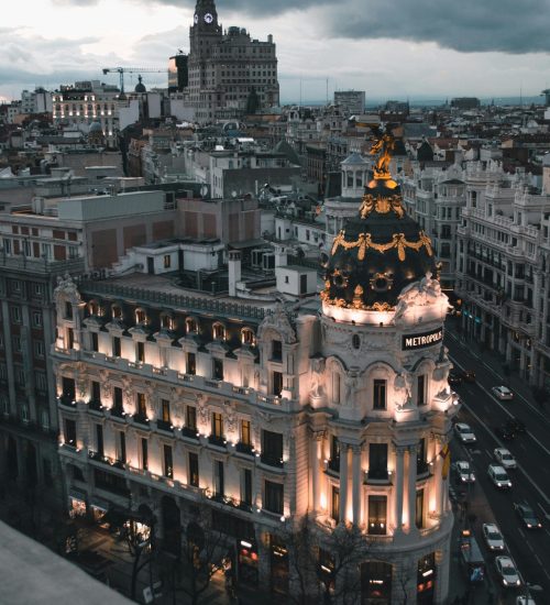 Aerial view of Madrid's Metropolis Building illuminated at dusk, showcasing urban architecture.