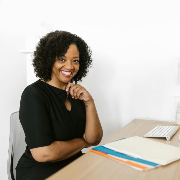 Happy woman sitting at a desk in a bright modern office, smiling confidently.