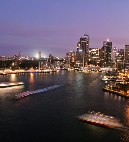 Captivating view of Sydney's illuminated skyline with the iconic Opera House and harbor at night.